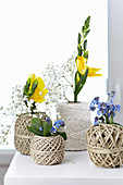Balls of twine used as vases containing freesias, forget-me-nots and gypsophila
