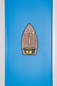 Kleines Kreuz mit Messingschale an blau getönter Wand