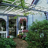 Pergola above paved garden patch with view into roofed veranda