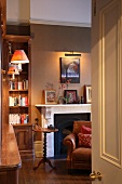 View through open door into room with fireplace and antique side table next to leather armchair