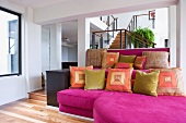 Large magenta sofa with several colorful throw pillows