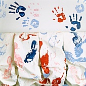 White fabric with colourful handprints and footprints
