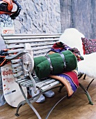 Lammwolldecken und Thermoskanne auf antiker Sitzbank vor Paneel in Steinwand-Optik