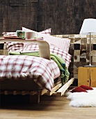 Bed with gingham flannel bed linen against wall clad in animal-skin patchwork and wood