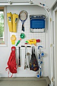 Sporting equipment and toys hanging on wall organiser in garage