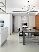 Grauer minimalistischer Tisch und Stühle unter Designer Hängelampe im offenen Esszimmer