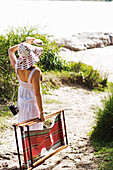 Frau mit Sonnenliege in der Hand am Strand