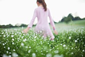 Girl walking in field of flowers