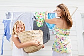 Girl helping mother hang laundry