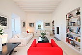 Roter Sessel und helle Sofagarnitur im Wohnraum eines mediterranen Landhauses