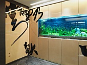 Chinesische Zeichen auf Wandverkleidung und beleuchtetes Aquariumfenster mit Pflanzen