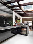Designer Küchenzeile mit Edelstahl-Spritzschutz und Naturstein-Arbeitsplatte unter einem Glasdach