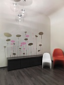 Stilisierte Blüten als Wanddekor hinter Sideboard und 70er Jahre Kugelleuchten zu Designerstühlen aus den Fifties