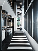 Open wardrobe and black and white striped flooring in the hallway of a loft-like living room