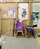 Colourful plastic nesting chairs and wooden storage boxes in front of DIY partition wall
