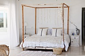 Romantische Häkeldecke und aufgefädelte Perlmutt-Scheiben als Dekoration am Baldachin eines Vintage-Bettes