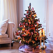 Goldene Bodenkerzenständer vor geschmücktem Weihnachtsbaum in Wohnzimmerecke mit traditionellem Flair