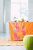 Printed tablecloth on table and convex stool in front of window