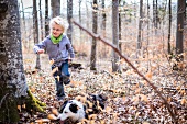 Kleiner Junge und Hund im herbstlichen Wald