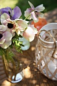 Flowers in bottle and tealight holder on wicker table mat