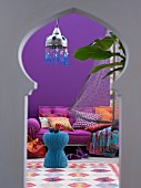 View of blue wicker table and mattress sofa in interior with Oriental ambiance through keyhole window