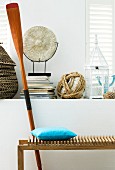 Wooden bench & paddle in front of various ornaments on masonry shelf