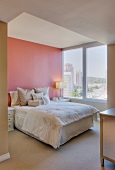 Ein Schlafzimmer mit grossem Fenster und rosa Wand