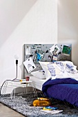 Teenager's bed and bedside table with metal frame and metal pinboard as headboard on flokati rug