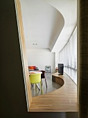 Blick durch Öffnung in Wand auf geschwungene Fensterbank aus Holz in modernem Wohnraum