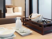 Tea service next to a rice wine carafe with porcelain bowls on an Asian style tray