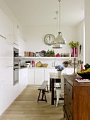 White built in kitchen with vintage dining table, bench and sideboard