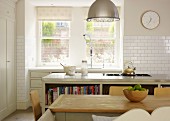 Country-house charm- simple dining table in front of kitchen island with hob and counter with sink below window