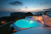 Der beleuchtete Swimmingpool einer mallorquinischen Villa in dramatischer Abendstimmung
