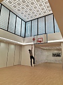 Sportlicher Mann in modernem Raum mit Basketballkorb an Wand