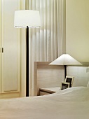 Minimalistischer Schwarzweiss-Look im Schlafzimmer mit Stehlampe und Tischlampe auf integriertem Nachttisch