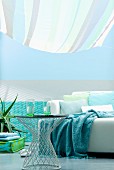 Living area in shades of aqua with sofa and side table below striped awning