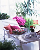 White lacquer outdoor lounger with pillows and potted tulips on a tray