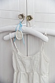 Dress with spaghetti straps on clothes hanger hanging on wardrobe door