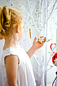 Little girl looking at Christmas biscuits hanging on tree