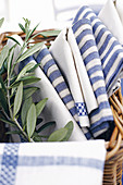 Various blue and white cloths and olive sprig in basket