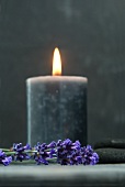 Lit candle amongst dried lavender and flat stones