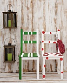 Two chairs - one with green and white stripes the other with red polka dots - in front of a wooden wall with lanterns