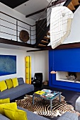 A blue fireplace and yellow accents define the modern style of this open living room with gallery