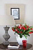 Tulips in white vase next to bedside lamp