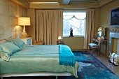 Edles Schlafzimmer mit Kamin und changierender Taftbettwäsche auf einem Doppelbett