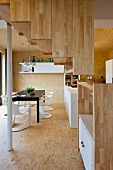 Wood-clad staircase in open-plan interior with modern dining area