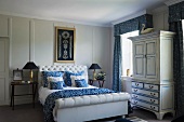 Double bed with white, upholstered headboard in traditional bedroom with blue and white colour scheme