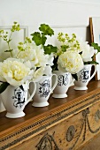 White roses in china jugs on carved wooden mantelpiece