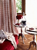 Elegant, chrome bistro table on parquet floor in front of window with floor-length curtains in boudoir