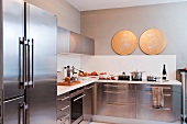 Modern kitchen with stainless steel cabinets and white back splash; to round, gold colored discs as focal points